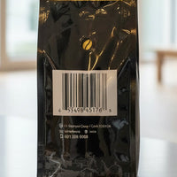 Black coffee bag with a reflective label on a light grey background
